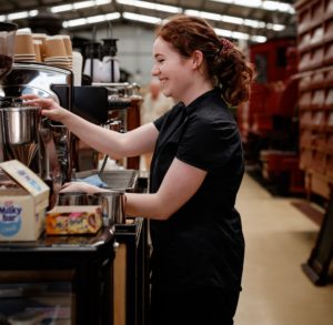 A smiling barista is making espresso coffee at the Puffing Billy's Menzies Creek Museum Cafe