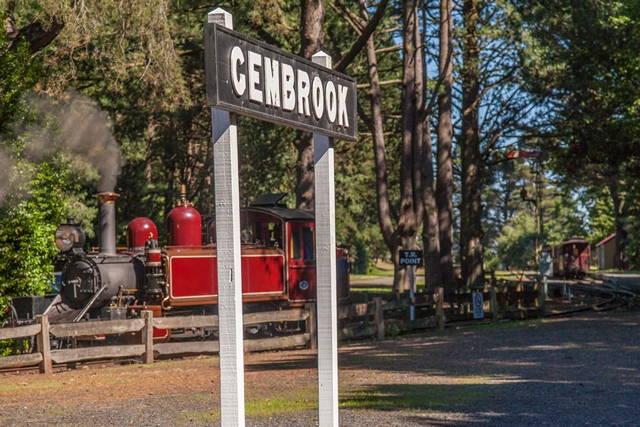 Gembrook station sign. A red steam locomotive can be seen in the background.