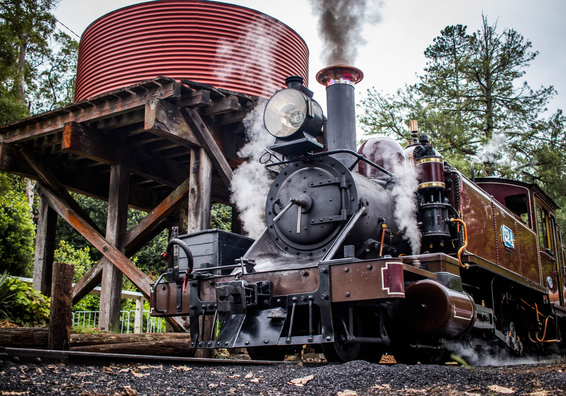 Puffing Billy locomotive next to a water tank, as it is being filled up with water in preparation for its return journey.