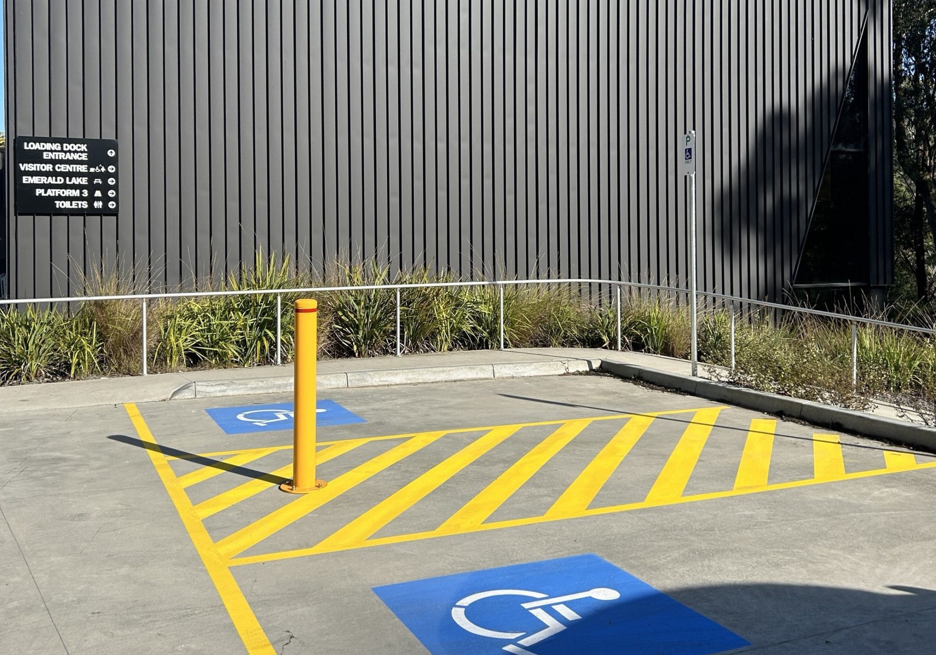 Two accessible car parking spots next to a building with black cladding.