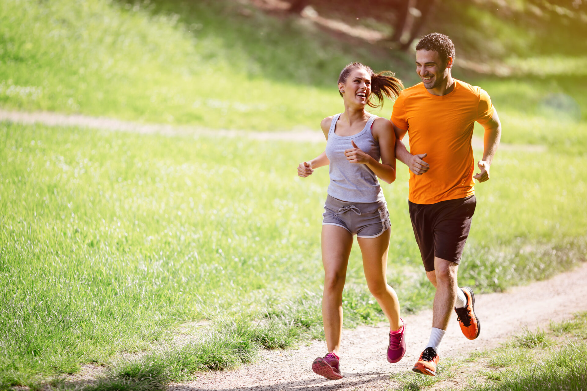 Couple Jogging through parkland in the sunshine.